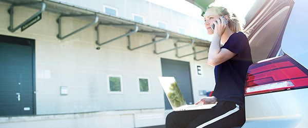 Telefonabonnement til erhverv Telefonabonnement til erhverv med fleksibel firmatelefoni der gør det muligt at arbejde på farten, som vist med en kvinde der sidder bag på en bil og snakker i telefon