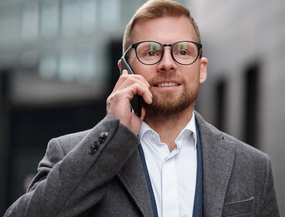 Medarbejder med mobiltelefon og et erhvervsmobilabonnement tilpasset arbejdsdagens behov. Det bedste mobilabonnement til erhverv er det, der passer til din hverdag
